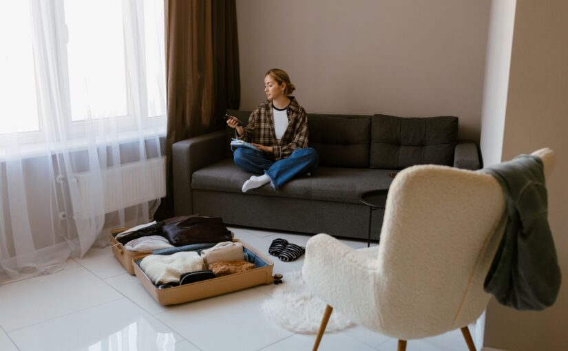 Frau sitzt nachdenklich auf dem Sofa mit geöffnetem Koffer – Symbolbild für einen Neuanfang nach der Scheidung